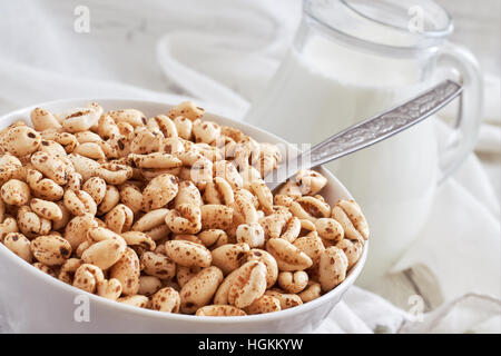 Aufgeblasen Weizenbrei in weiße Schüssel mit Krug Milch im Hintergrund Stockfoto