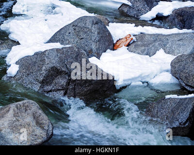 Schnee, Eis und Granit Felsblöcke in einem kleinen Bach im Yosemite Valley auf einem Ocld Wintertag. Stockfoto