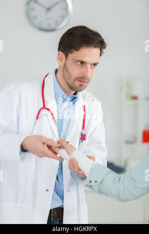 Arzt seine Patienten Hand in Arztpraxis Bandagierung Stockfoto