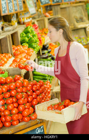 Shop Mitarbeiter tragen eine Kiste Tomaten Stockfoto