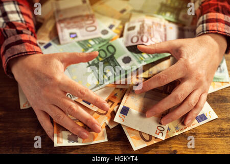 Gierige Hände Aberkennung der Haufen von Euro-Banknoten Bargeld auf Schreibtisch Stockfoto