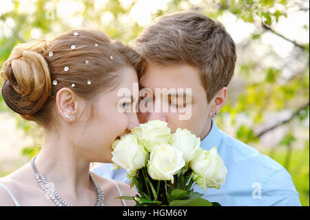 Braut und Bräutigam im Frühlingspark riechen eine weiße rose Stockfoto