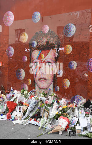 Floral Tribute links von den Fans von David Bowie auf das Wandbild in Brixton am ersten Jahrestag seines Todes, London.UK Stockfoto