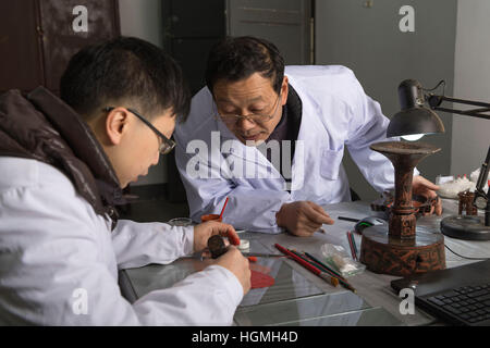 (170111)--JINGZHOU, 11. Januar 2017 (Xinhua)--Du Daozi (R) führt sein Kollege auf Farbe für die Reparatur von Lackarbeiten im Kulturdenkmal Erhaltung Center in Jingzhou Stadt, Zentral-China Hubei Provinz, 10. Januar 2017 mischen. Du Daozi ist ein Spezialist für Bambus und Holz Lacquerware Restaurierung. Er wurde in Jingzhou Museum eingeführt und Lack Restaurierungsarbeiten im Jahr 1987 begann. In den vergangenen 30 Jahren hat Du mehr als 2.000 Stück der Lacquerwares, einschließlich viele kulturelle Relikte von großem historischen Wert wiederhergestellt. (Xinhua/Xiong Qi) (Swt) Stockfoto