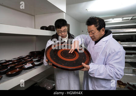 (170111)--JINGZHOU, 11. Januar 2017 (Xinhua)--Du Daozi (R) untersucht eine restaurierte Lackarbeiten im Kulturdenkmal Erhaltung Center in Jingzhou Stadt, Zentral-China Hubei Provinz, 10. Januar 2017. Du Daozi ist ein Spezialist für Bambus und Holz Lacquerware Restaurierung. Er wurde in Jingzhou Museum eingeführt und Lack Restaurierungsarbeiten im Jahr 1987 begann. In den vergangenen 30 Jahren hat Du mehr als 2.000 Stück der Lacquerwares, einschließlich viele kulturelle Relikte von großem historischen Wert wiederhergestellt. (Xinhua/Xiong Qi) (Swt) Stockfoto