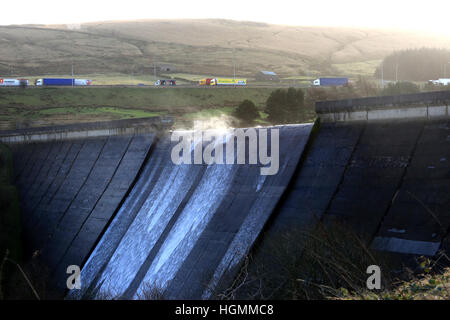 Stand Holz Dam, Rishworth, Ripponden, UK. 11. Januar, 2017.Trucks in der Ferne auf die M62, Englands höchste Autobahn, da Winde zwingen Wasser über Stand Holz Verdammung, Rishworth, Ripponden, 11. Januar 2017 © Barbara Koch/Alamy Live News Stockfoto