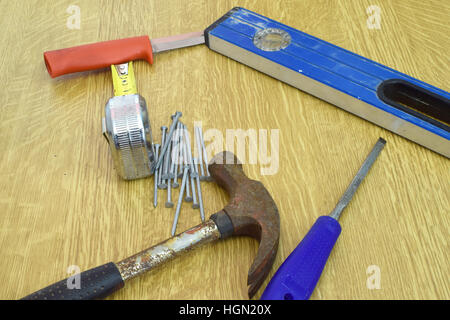 Hammer, Nägel, Messer, Lineal, Wasserwaage und Meißel auf den Tisch. Stockfoto