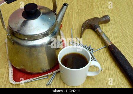 Kaffee-Wasserkocher, Tasse, alte Hammer und Nägel auf dem Tisch. Stockfoto