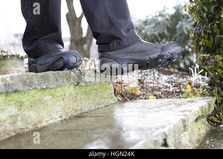 Ein Mann mit Schuh Schnee Spikes im Winter auf eisigen Treppe Stockfoto