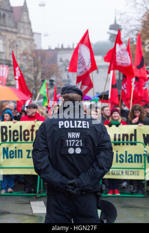 Ein deutscher Polizist steht vor einem Publikum von Demonstranten Stockfoto