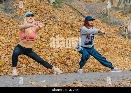 Zwei hübsche Frauen im Autamn Park. Blond und afrikanischen Frauen training unter freiem Himmel Stockfoto