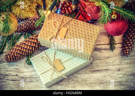 Retro-Overhead Schuss auf Kartons dekoriert mit String und Etikett auf einem Holztisch unter Weihnachtsbaum mit Zapfen Stockfoto