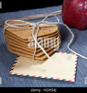 Geschenk zum Valentinstag. Herzform Lebkuchen, Umschlag und Geschenk verpackt in einer Schachtel aus Wellpappe für einen lieben Menschen. Stockfoto