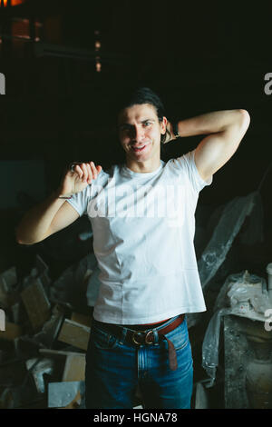 Schöne langhaarige Brünette Kerl Hände hinter seinem Kopf in weißen t-shirts Stockfoto