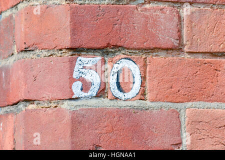 Haus Nummer 50 Zeichen auf roten Backsteinmauer weiß lackiert Stockfoto