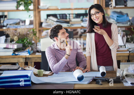 Junge Frau mit Smartphone im Büro Stockfoto
