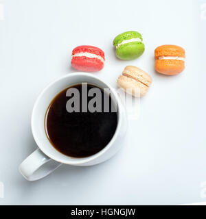 Süße und bunte Makronen mit Tasse Kaffee auf weißem Hintergrund. Traditionelles französisches Dessert. Ansicht von oben flach legen, Platz für text Stockfoto