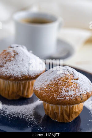 Frühstück mit Muffins, bestreut mit Puderzucker und Kaffee. Stockfoto