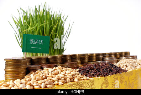 Saudi Arabien-Fähnchen mit Stapel von Geld Münzen und Haufen von Weizen und Reis Samen Stockfoto