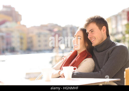 Paar, entspannend, sitzen in einer Hotelterrasse an Feiertagen mit einem Hafen im Hintergrund an einem sonnigen Tag des Winters Stockfoto