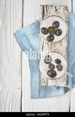 Chia Pudding mit Trauben auf dem vertikalen weißen Holztisch Stockfoto