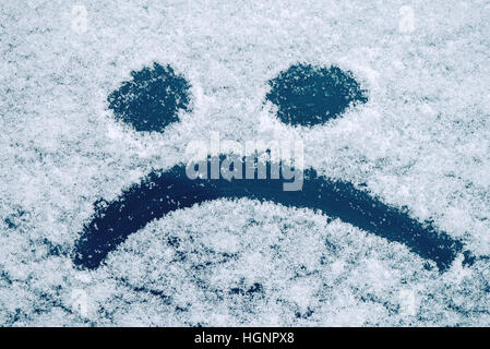 Traurige Smiley Emoticon Gesicht gezeichnet auf schneebedeckten Glas, Winter Saison Traurigkeit Konzept Stockfoto