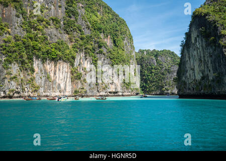 Dschungel-Kalkstein-Klippen rund um Phi Phi Leh Insel mit touristischen Boot Parkplatz Stockfoto