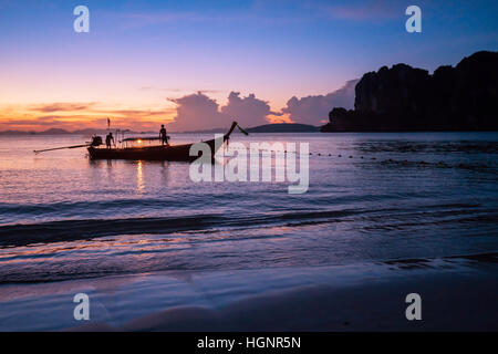 Tropical Island-Sonnenuntergang mit Fischerboot in der Silhouette, mit orangenen und blauen Tönen auf der Insel Phi Phi Leh Stockfoto