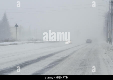 Bukarest, Rumänien, 25. Januar 2016: Autos werden auf einer verschneiten Straße in einem Schneesturm in Bukarest bestanden. Stockfoto