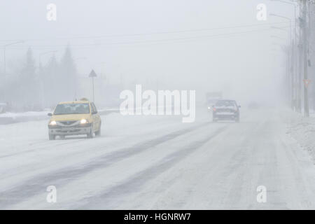 Bukarest, Rumänien, 25. Januar 2016: Autos werden auf einer verschneiten Straße in einem Schneesturm in Bukarest bestanden. Stockfoto