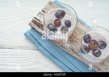 Chia Pudding mit Trauben auf dem weißen Holztisch Stockfoto