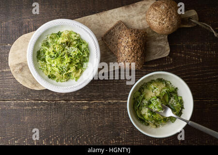 Zucchini-Nudeln mit Käse und Brot auf dem Holztisch Draufsicht Stockfoto