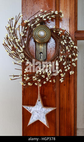 Rustikale Kranz und Star Weihnachtsschmuck an eine antike Tür hängen. Stockfoto