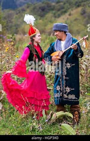 Kasachische Paar in Nationalkostümen mit Mann spielt lokale Musikinstrument von Dombra, Kasachstan Stockfoto