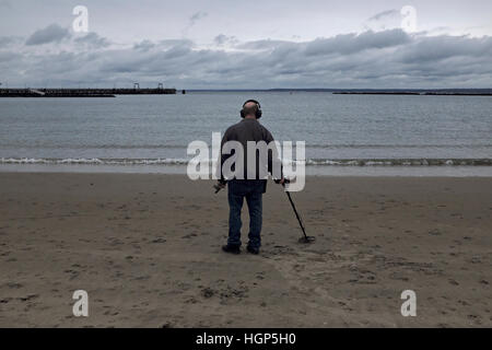 RYE, New York: Ein Mann nutzt einen Metalldetektor an einem Strand in der Nähe von Roggen Playland Park. 09.10.16 Stockfoto