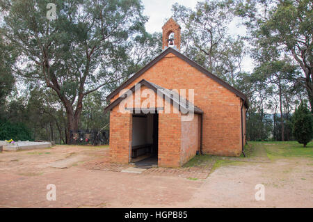 All Saints Church Ziegelarchitektur mit Bell, Grabstellen und einheimische Bäume in der Dämmerung in Henley Brook, Western Australia. Stockfoto