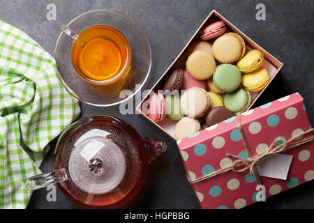 Teetasse, Teekanne und Makronen Geschenkbox am Steintisch. Ansicht von oben Stockfoto