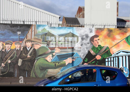 Auto fahren auf der Straße fällt in Belfast an der internationalen Friedens-Mauer vorbei Stockfoto