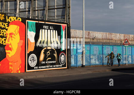 Touristen auf der Straße fällt in West Belfast vorbei an der internationalen Friedensmauer nurals Stockfoto