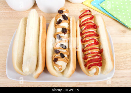 Bananen-Hund-Sandwiches auf rechteckigen Platte, gelb, grün und blau polka Dot Servietten Tassen hinter im Hintergrund. Banane in einem Hot-Dog-Brötchen, schlicht, mit pe Stockfoto