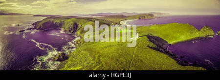 Surreale aerial Landschaft von Meer, Land und Leuchtturm in grün und lila Farben Stockfoto