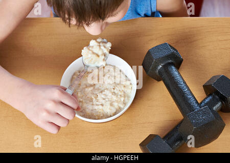 Junge essen Brei und Hanteln als Symbole der Sport lifestyle Stockfoto