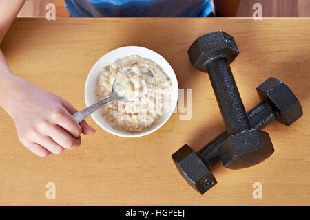 Junge essen Brei und Hanteln als Symbole der Sport lifestyle Stockfoto