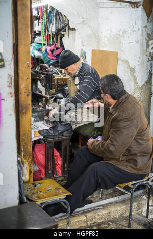 Mann sitzt vor einem Schuhmacher-Werkstatt in der Jerusalemer Altstadt, Israel Stockfoto