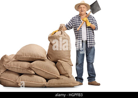 In voller Länge Portrait von Reifen Bauer mit einem Schaufel stehen neben einem Haufen von Sackleinen Säcke isolierten auf weißen Hintergrund Stockfoto