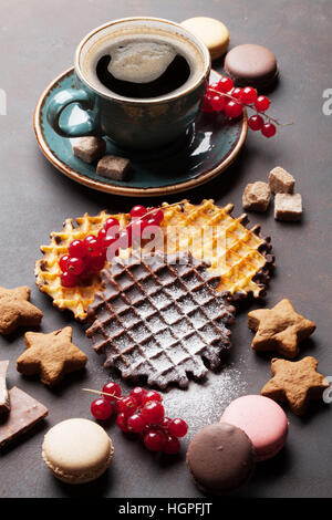 Kaffee mit Waffeln und Süßigkeiten am Steintisch Stockfoto