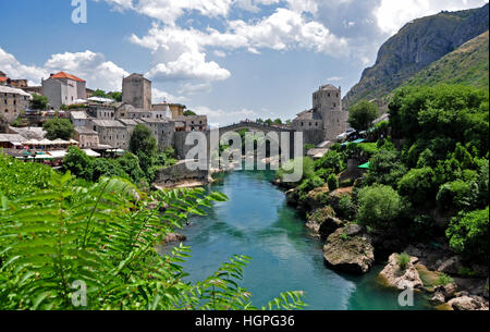 aus dem 16. Jahrhundert osmanischen Brücke über einen Fluss in einem Bergdorf in Bosnien-Herzegowina, mit blauen bewölkten Himmel und Sonne Stockfoto