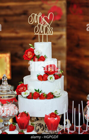 schönen dreischichtigen Hochzeitstorte dekoriert mit roten Blüten Stockfoto