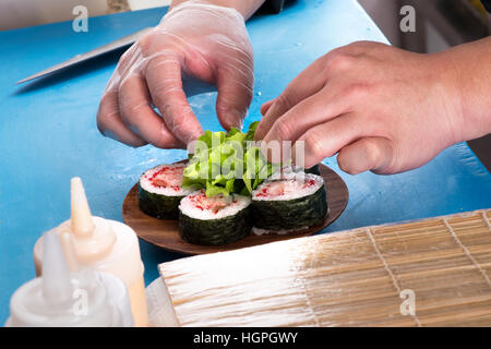 Nahaufnahme der Köche Hände sorgfältig platzieren Futomaki rollt auf Holzplatte Stockfoto