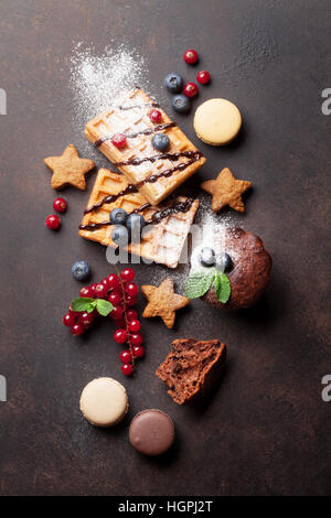 Waffeln, Bonbons und Süßigkeiten am Steintisch. Ansicht von oben Stockfoto